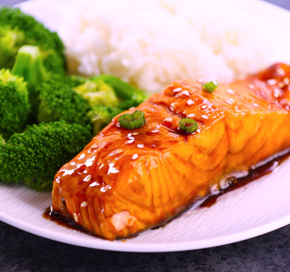 Gorgeous baked salmon glazed with a homemade honey garlic sauce on a serving plate with broccoli on the side for an easy weeknight dinner idea that's ready in about 20 minutes.