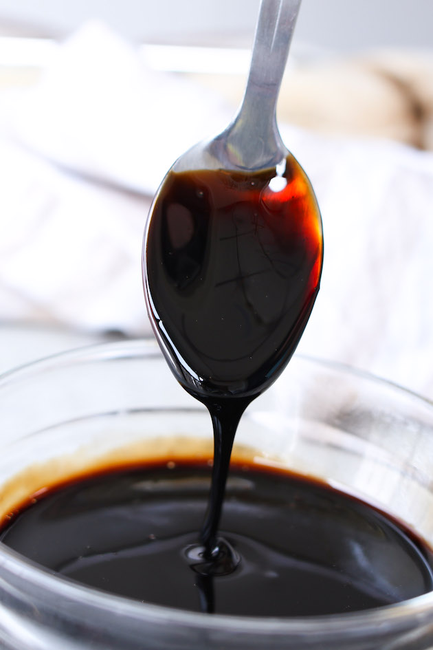 Balsamic reduction coating a serving spoon showing it's glaze-like consistency and rich deep color. This versatile condiment add a burst of flavor to meats, seafood, salads, fruits and even ice cream! 