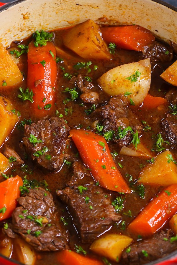 Closeup of chunks of beef, carrots and potatoes in a rich sauces with minced fresh parsley on top