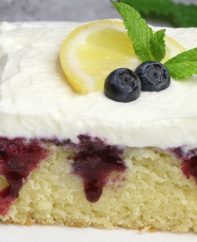 Blueberry Lemon Poke Cake – bursting with irresistible lemon and blueberry flavor. The lemon cake is poked with holes, and drizzled with lemony and sweet blueberry sauce, then topped with whipped cream. So Good! Perfect for a holiday party! Easy recipe. Vegetarian. Video Recipe | Tipbuzz.com