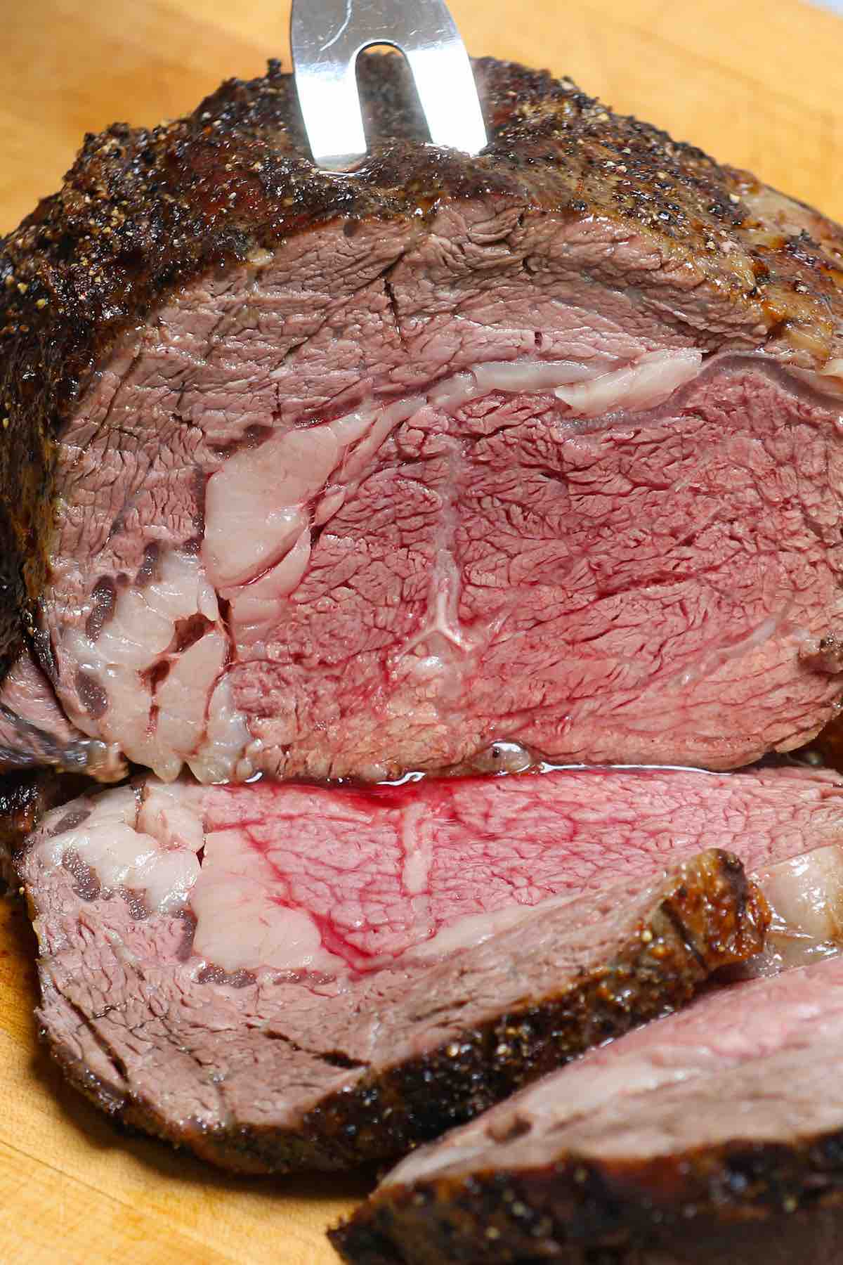Closeup of carving a boneless prime rib roast cooked medium with a warm pink center