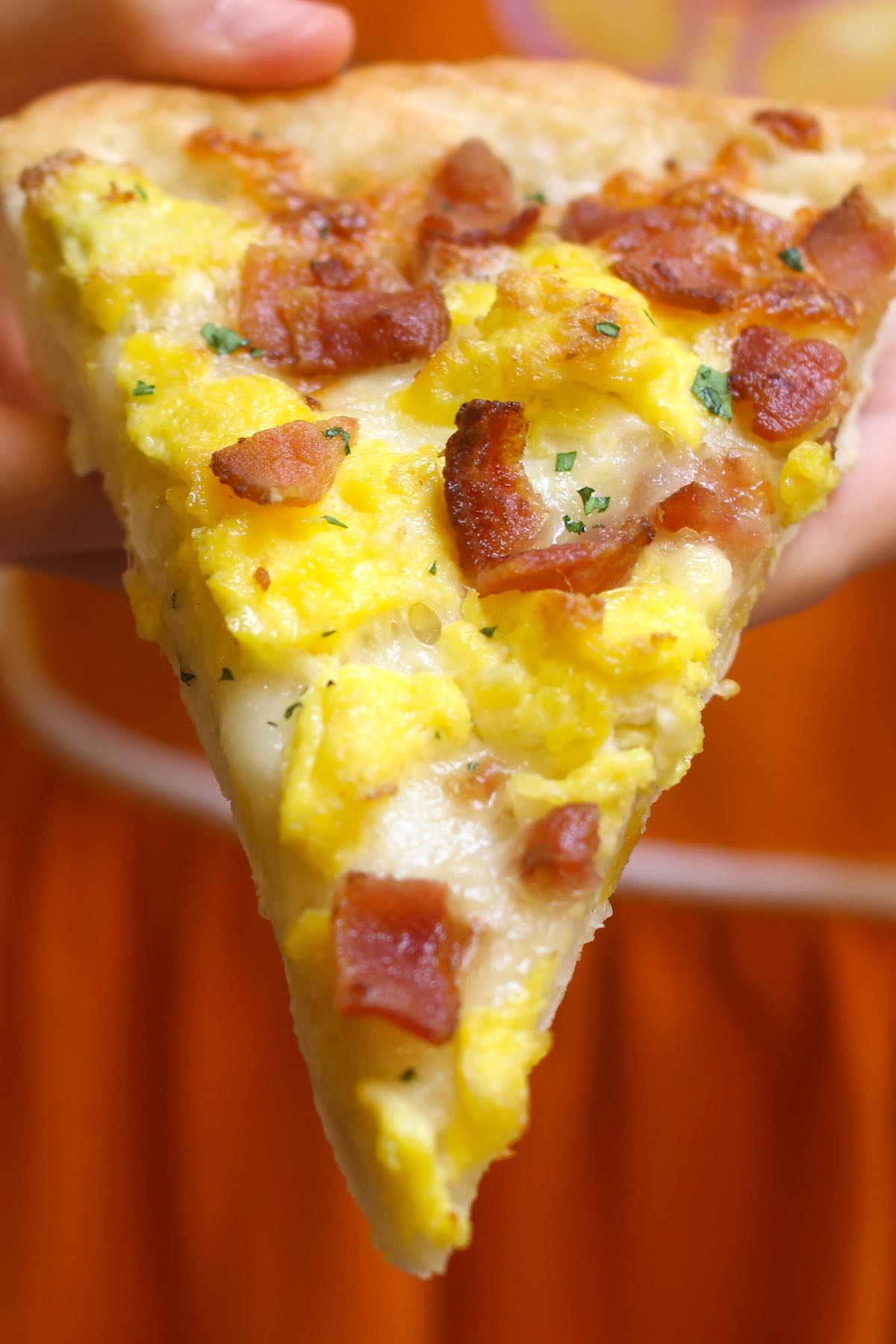 A slice of bacon, egg and cheese breakfast pizza fresh out of the oven. 