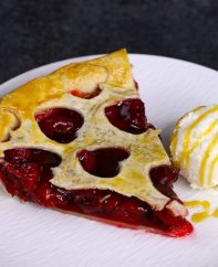 A serving of homemade cherry pie with ice cream on the side