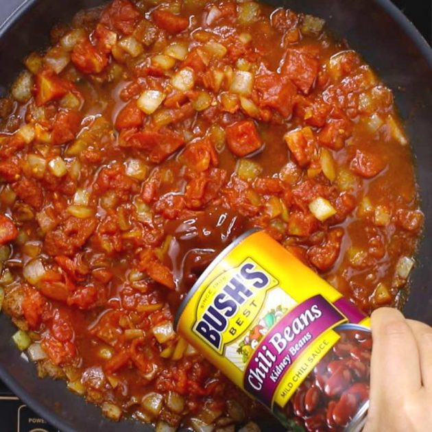 This photo shows adding Bush's Chili Beans to the chili in a skillet #AD