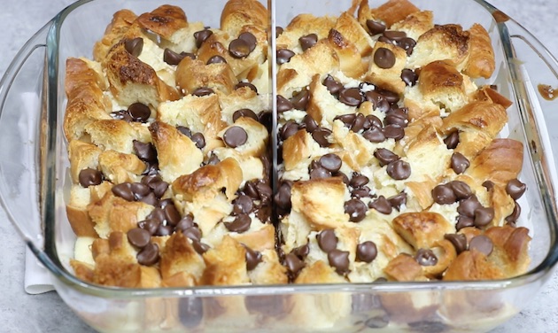 Slicing chocolate croissant bread pudding in a baking dish