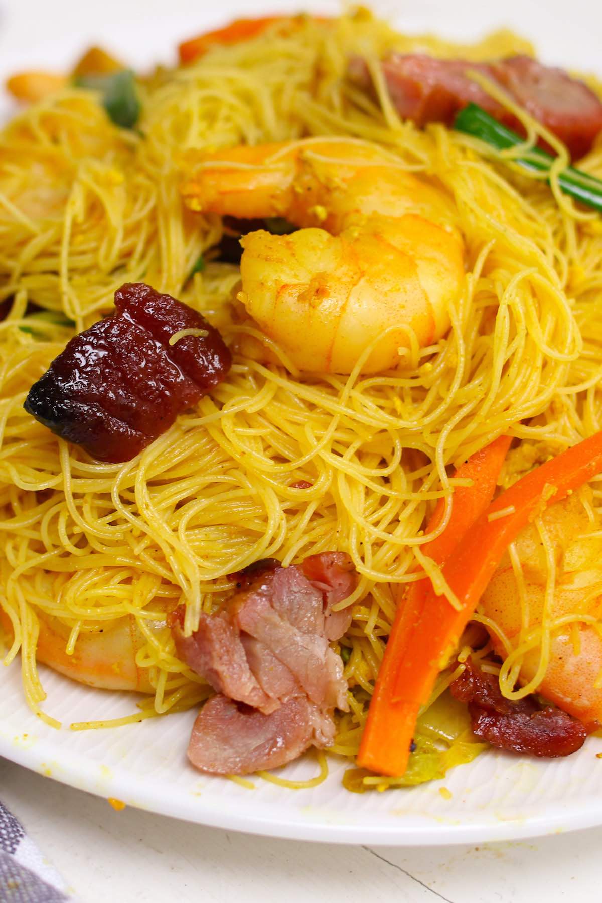 Closeup of Singapore chow mei fun showing the vermicelli rice noodles, barbecue pork, shrimp and vegetables