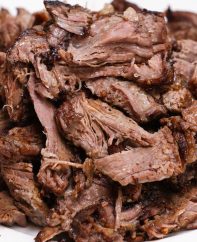 A mound of tender pulled chuck roast on a serving plate