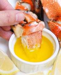 Jonah crab claws being dipped in melted butter