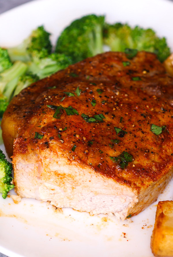Cross-section of a pork chop that's been seasoned and cooked to perfection and served with potatoes and broccoli.