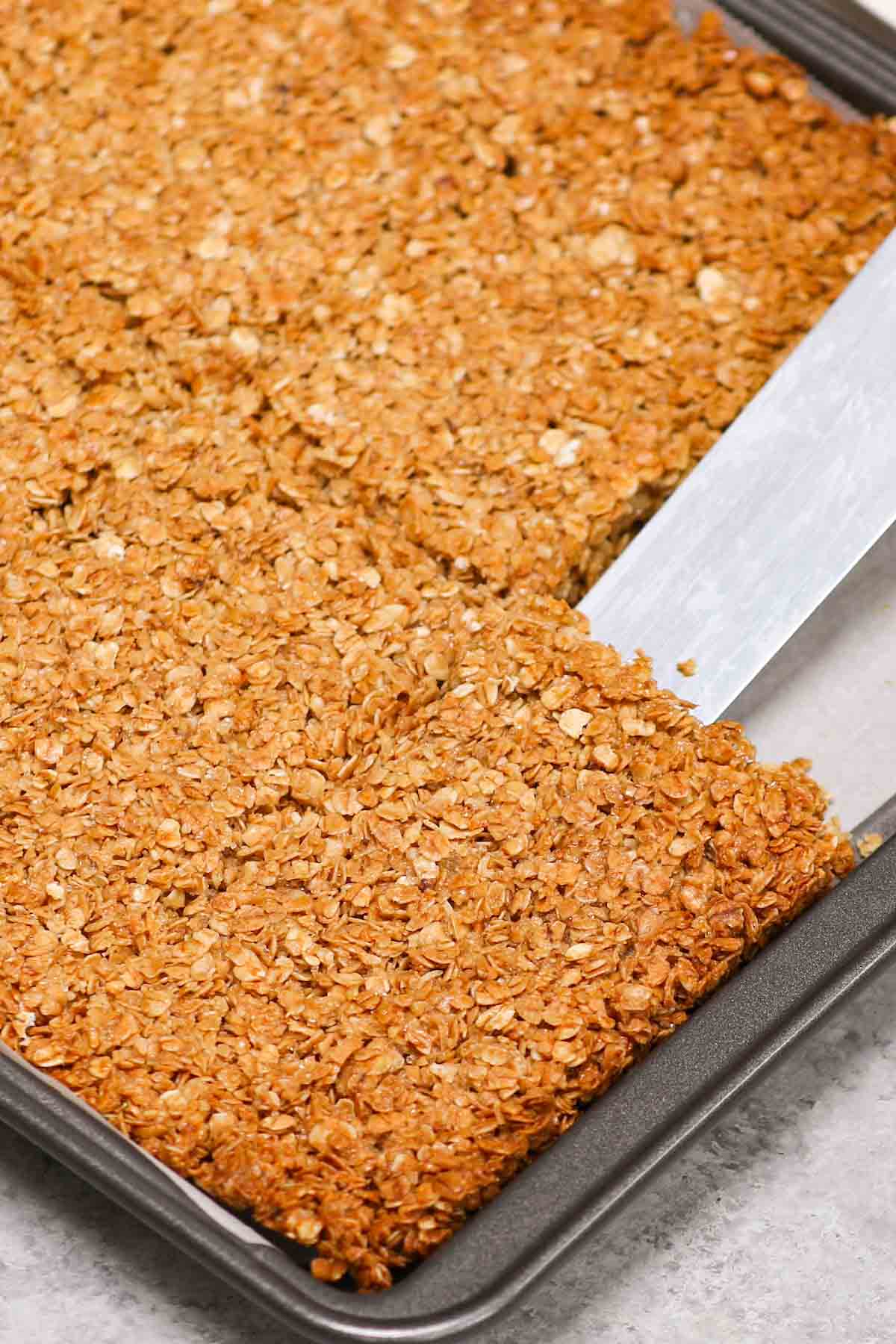 Lifting crispy dessert squares out of a baking sheet using a spatula