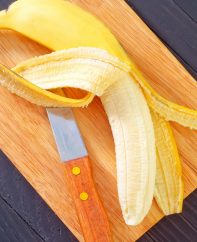 Peeling and slicing a ripe banana on a cutting board