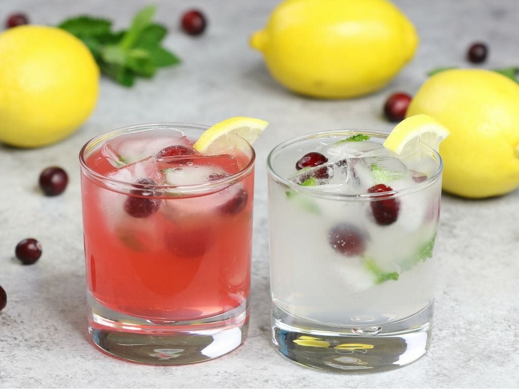Lemonade cocktails made two ways with Mike's Hard Lemonade original flavor and strawberry flavor, garnished with cranberries and mint