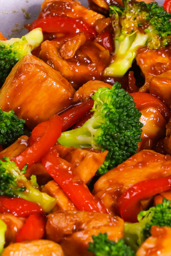 Closeup of chicken stir fry with cubed chicken, garlic, broccoli and bell peppers coated in a stir fry sauce
