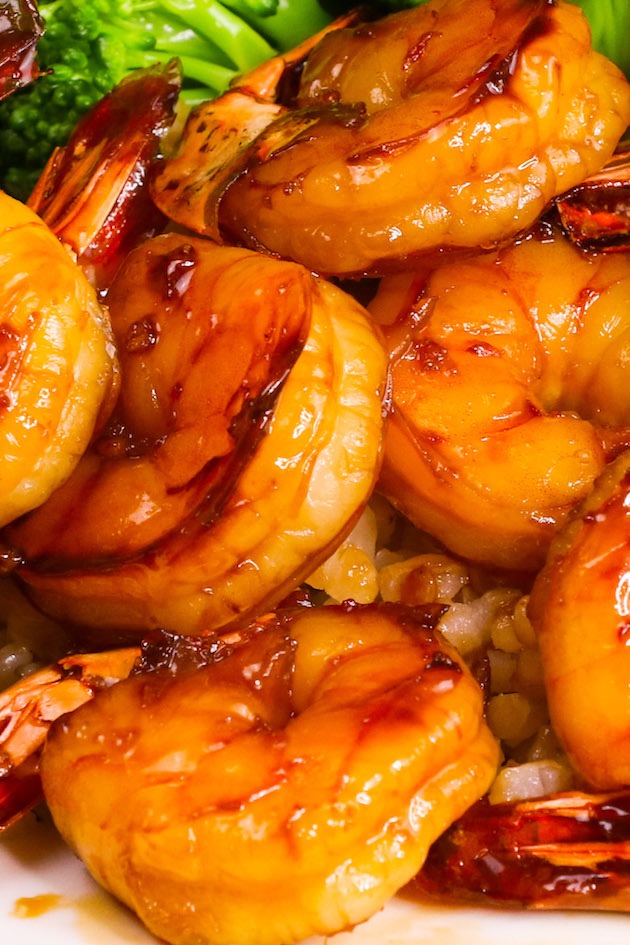 Sticky honey garlic shrimp served with rice and broccoli on a white plate