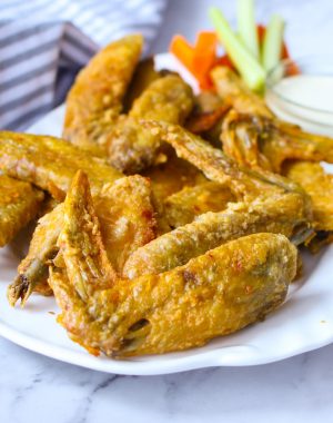 Crispy baked chicken wings on a serving platter with carrots, celery and ranch dip