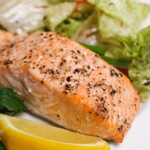 Oven baked salmon on a serving plate with a side salad