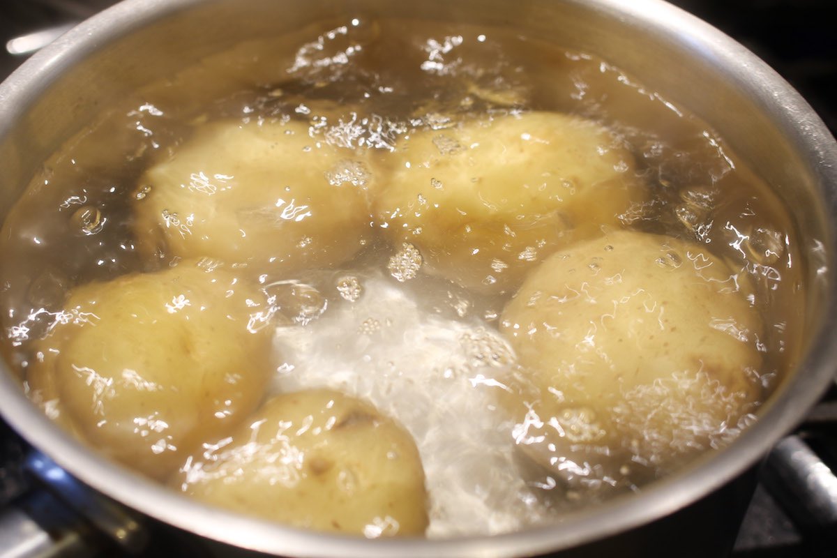 Closeup of round white potatoes in a pot full of boiling water