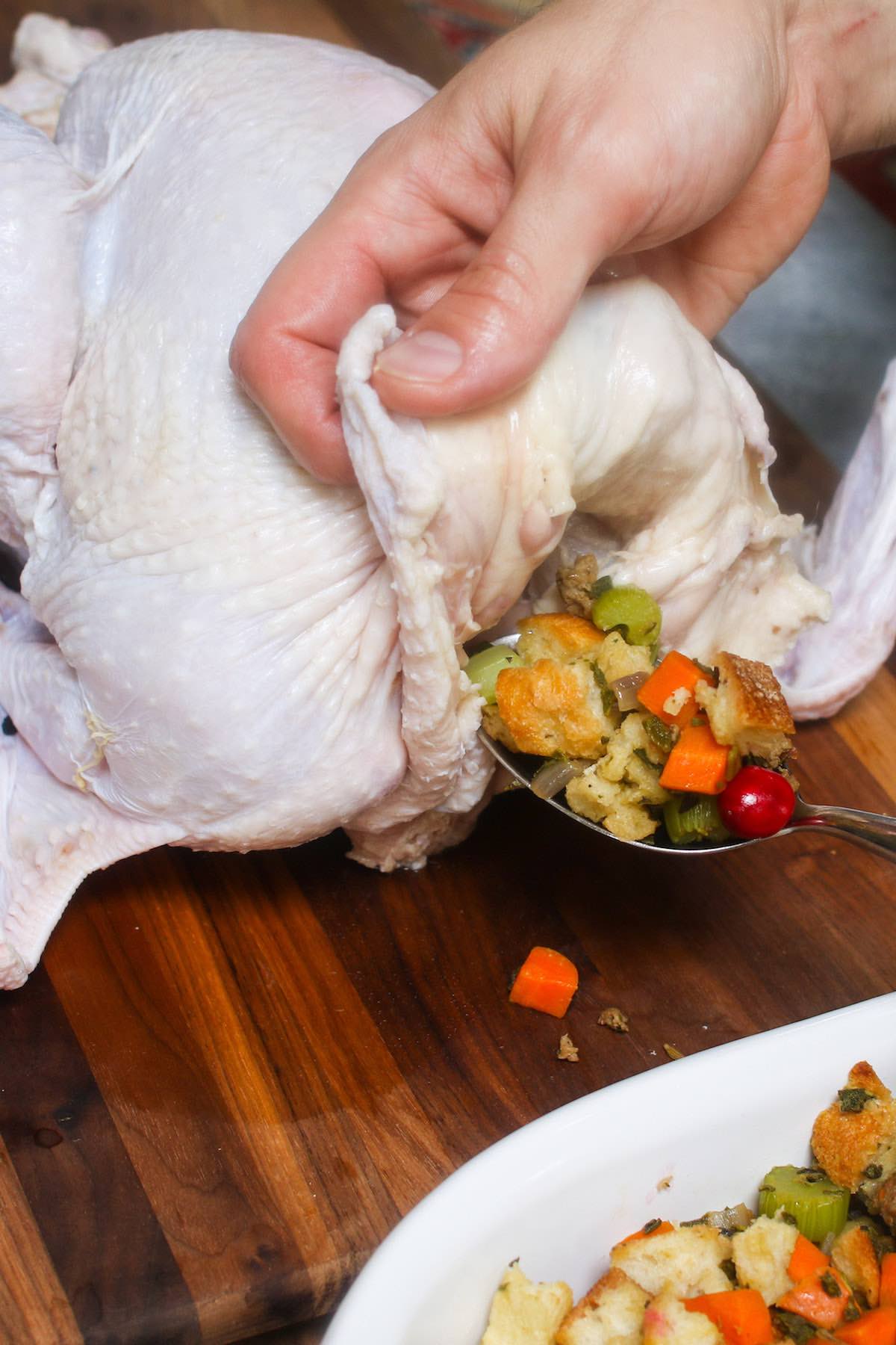 Stuffing a turkey from the neck end by lifting the flap of skin to expose the cavity