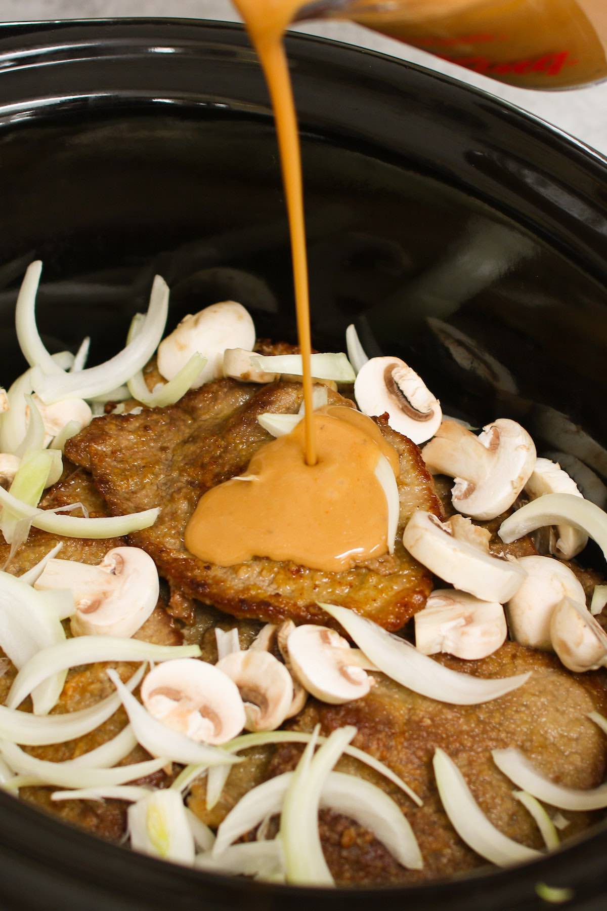 Drizzling gravy into the slow cooker when making smothered pork chops