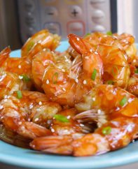 Instant Pot Shrimp with honey garlic sauce garnished with minced green onion and sesame seeds on a serving plate