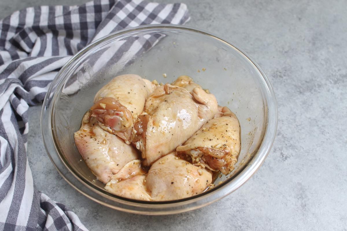 Marinating chicken thighs in a clear bowl.
