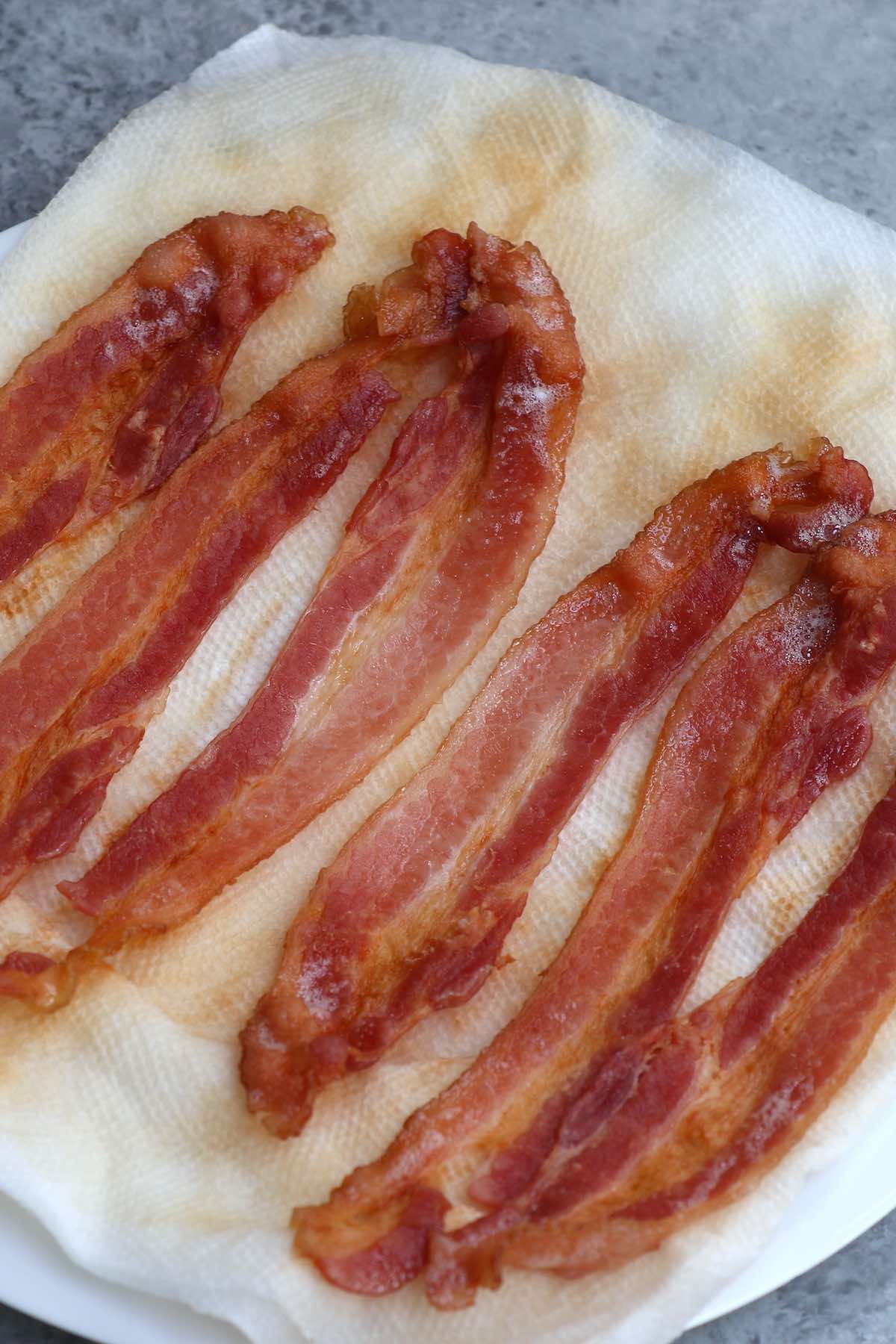 Six strips of crispy microwaved bacon on a paper towel lined plate 