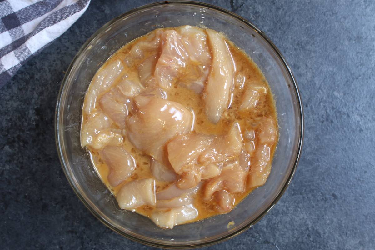 Sliced chicken slices marinating in rice vinegar, egg white and cornstarch when making moo goo gai pan.