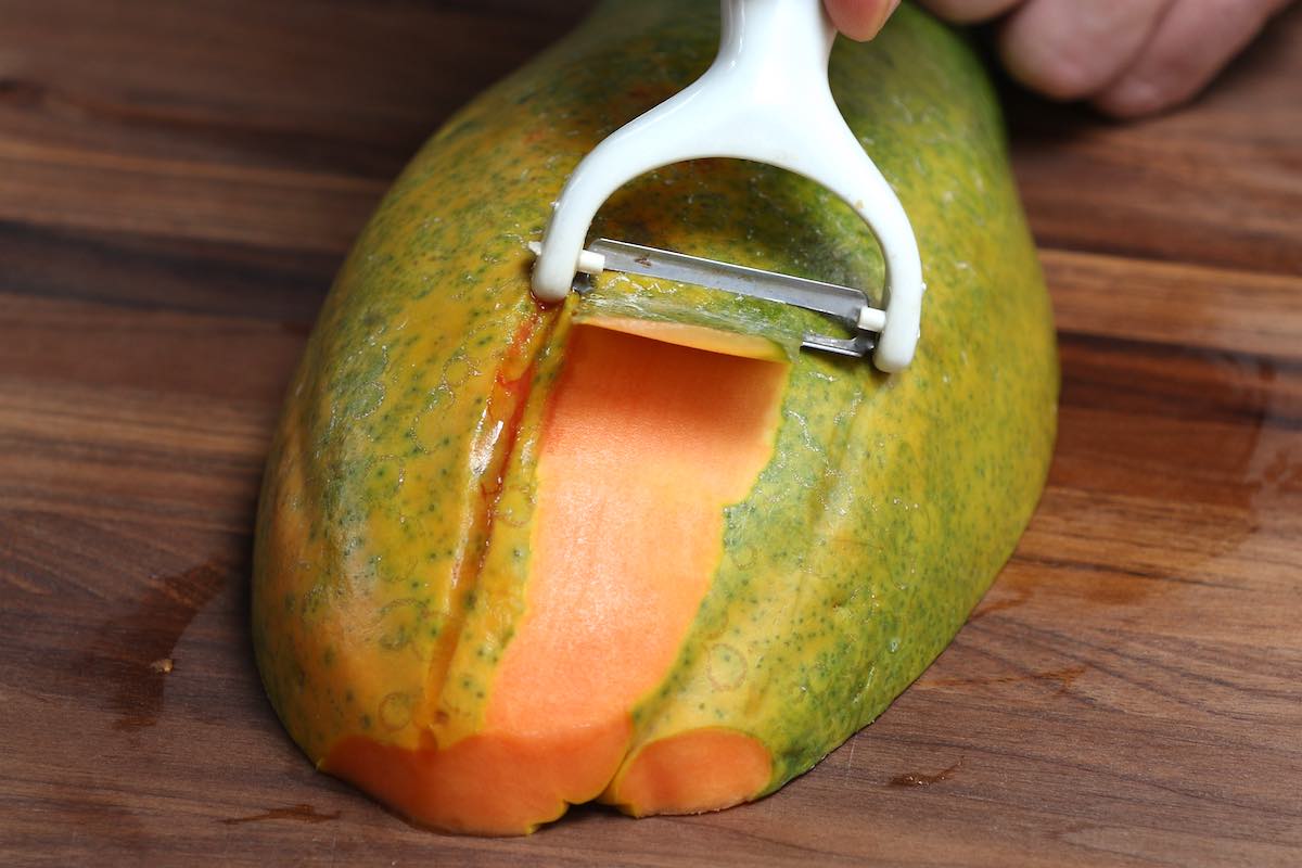 Using a vegetable peeler to remove a papaya's skin
