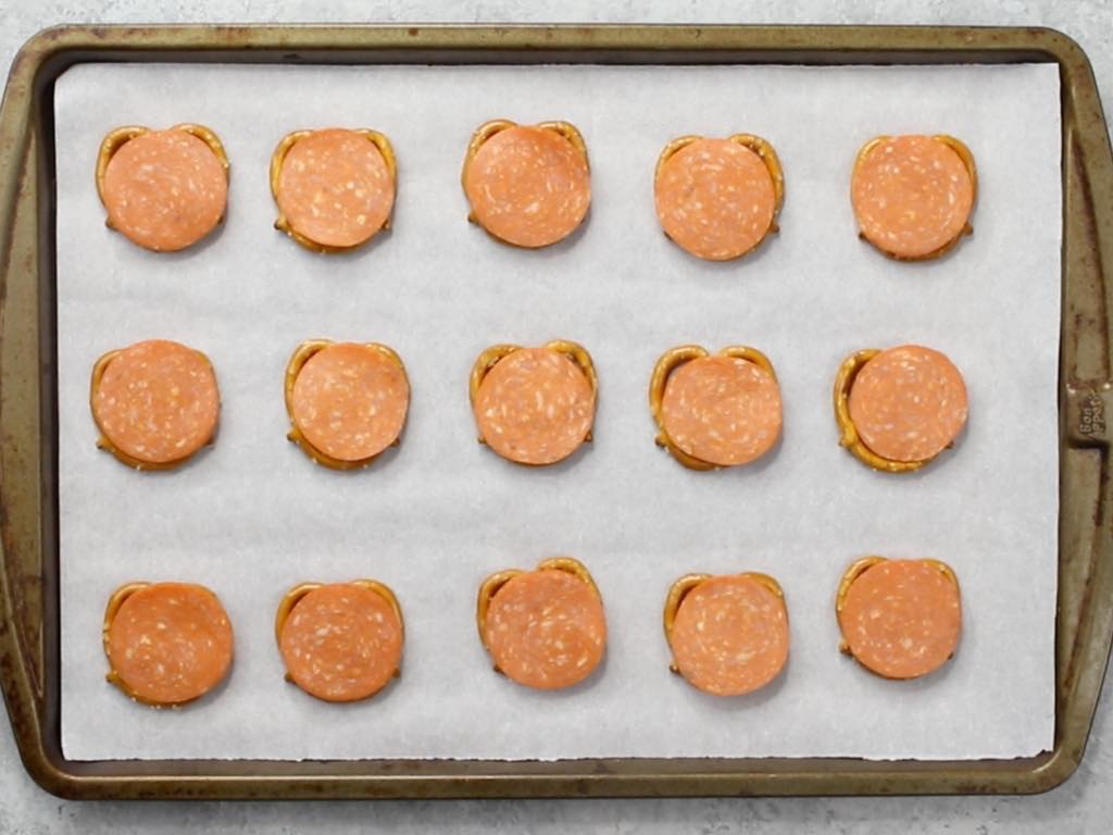 This photo shows pepperoni pizza pretzels arranged on a baking sheet lined with parchment paper