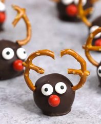 Reindeer Oreo Truffles consist of oreo cheesecake balls coated in dark chocolate and decorated in a reindeer theme for a cute holiday party treat or gift idea