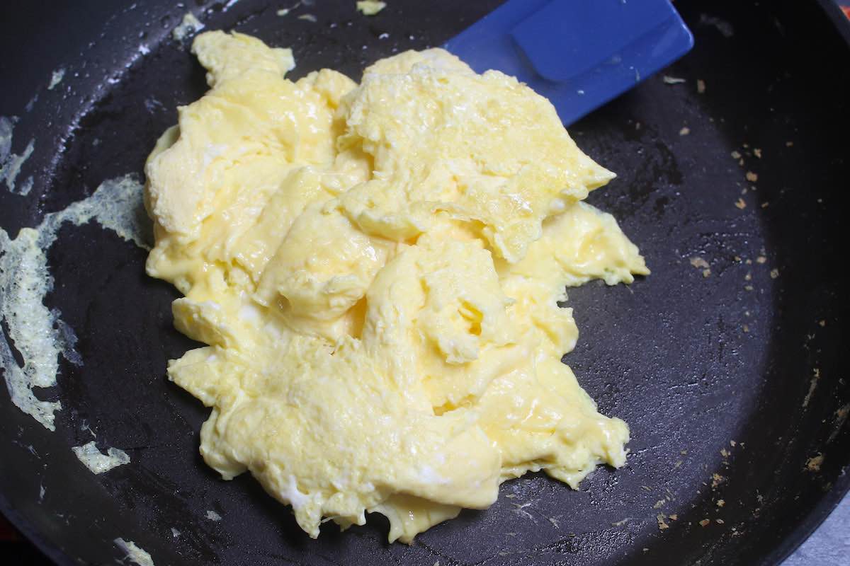 Scrambling eggs in skillet with a spatula until no liquid remains.