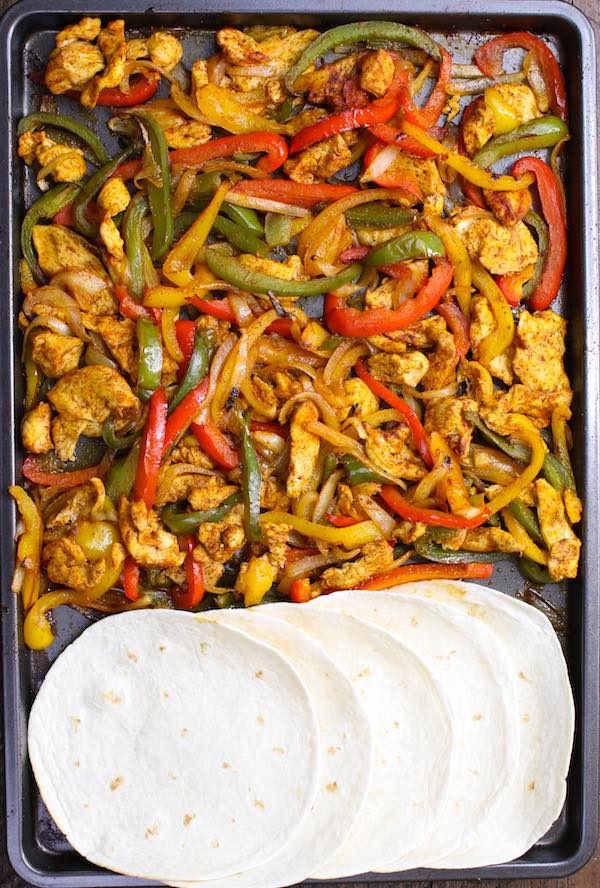 Sheet Pan Chicken Fajita – one of the easiest healthy dinner recipes. Yellow, red and green peppers, sliced onions and chicken breasts, mixed with some simple spices (ground cumin, chili powder, garlic powder, salt and olive oil). Perfectly baked in the oven, and served on flour tortillas. Simply Yummy! Make-ahead recipe. Quick and easy dinner recipe. | tipbuzz.com #ChickenFajitas #sheetPanChickenFajitas