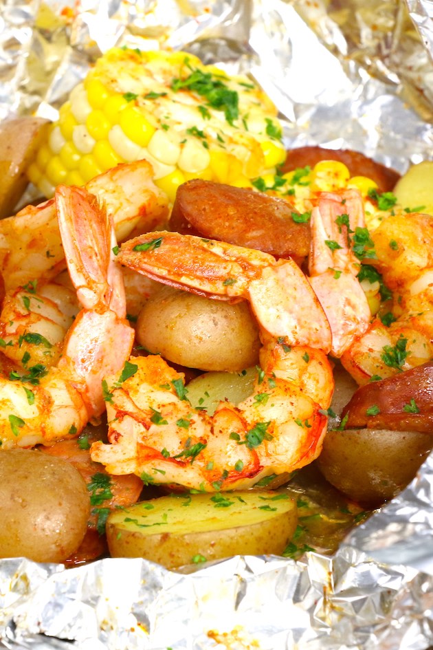 This shrimp boil in foil is a delicious combination of jumbo shrimp, baby potatoes, corn and sausage with Old Bay seasoning, grilled and garnished with lemon juice and parsley for a delicious Cajun meal
