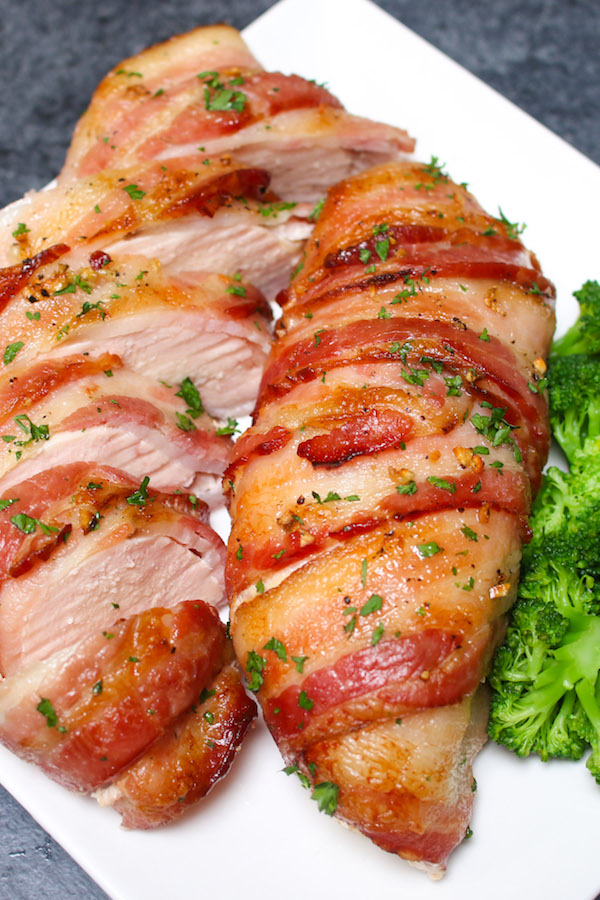Slow Cooker Bacon Garlic Chicken Breast on a serving plate showing tender and juicy chicken breast wrapped with crispy bacon garnished with fresh parsley with broccoli on the side