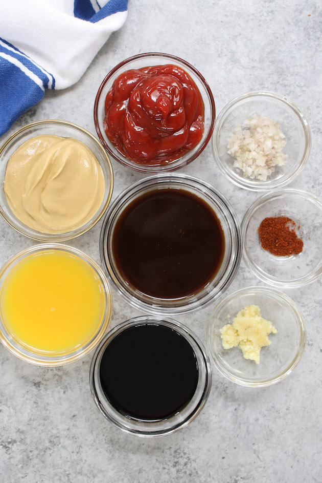 All ingredients displayed on the counter: ketchup, Dijon mustard, balsamic vinegar, orange juice, Worcestershire sauce, minced garlic, sliced shallot and cayenne pepper