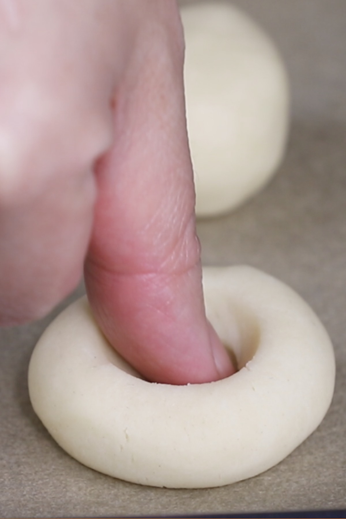 Close-up of pressing the tip of the thumb about a 1/2 inch into the middle of a cookie dough ball to make an imprint.