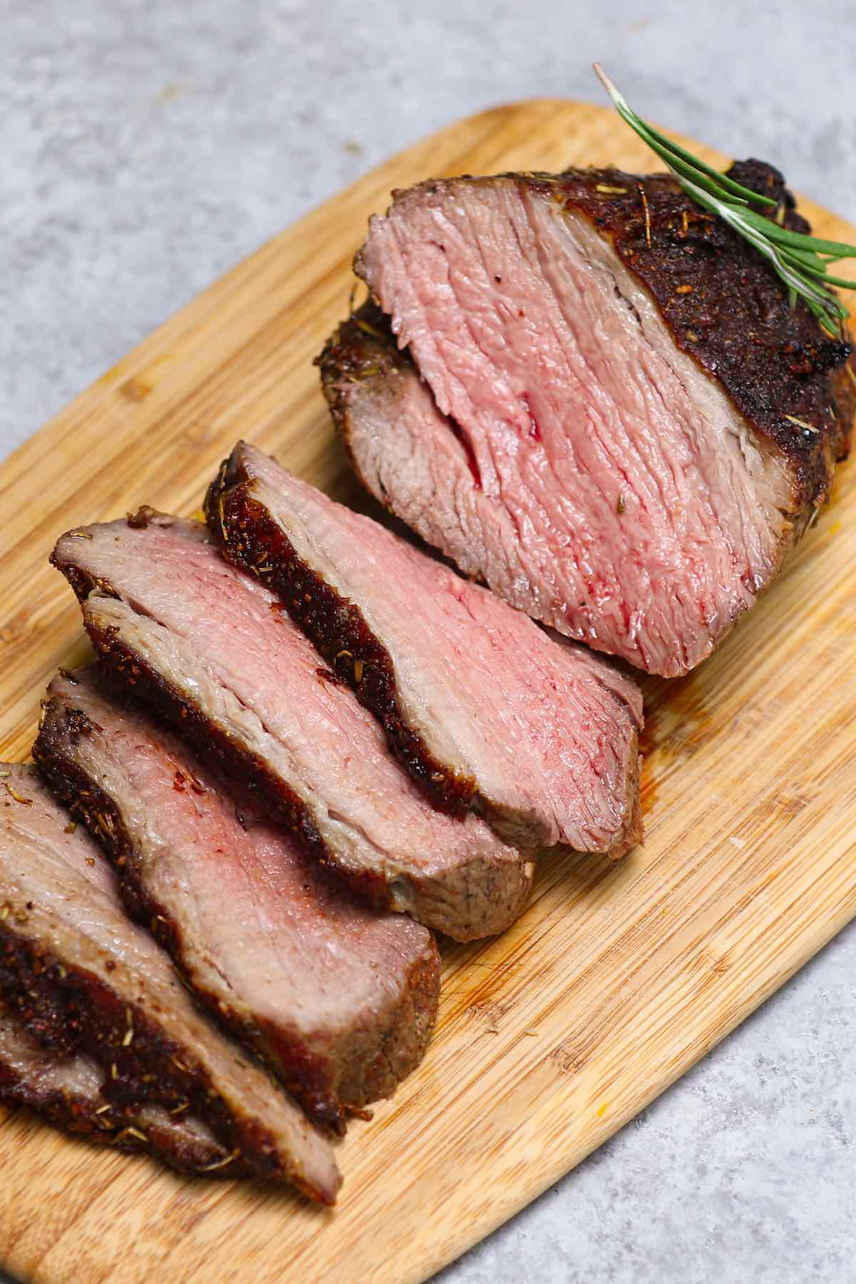 Slices of sirloin roast on a carving board showing medium doneness with a pale pink interior