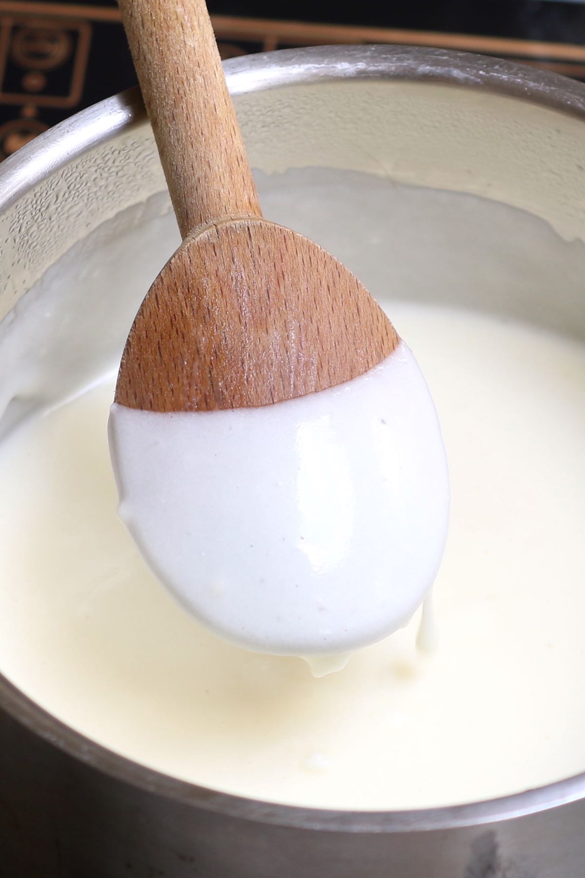 Bechamel sauce coating the back of a wooden spoon once thickened