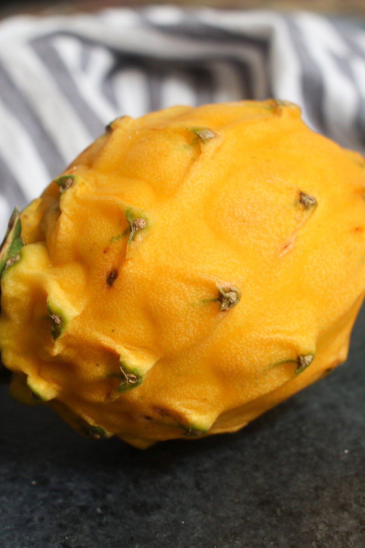 Closeup of a yellow pitaya with a few small blemishes which are not a concern